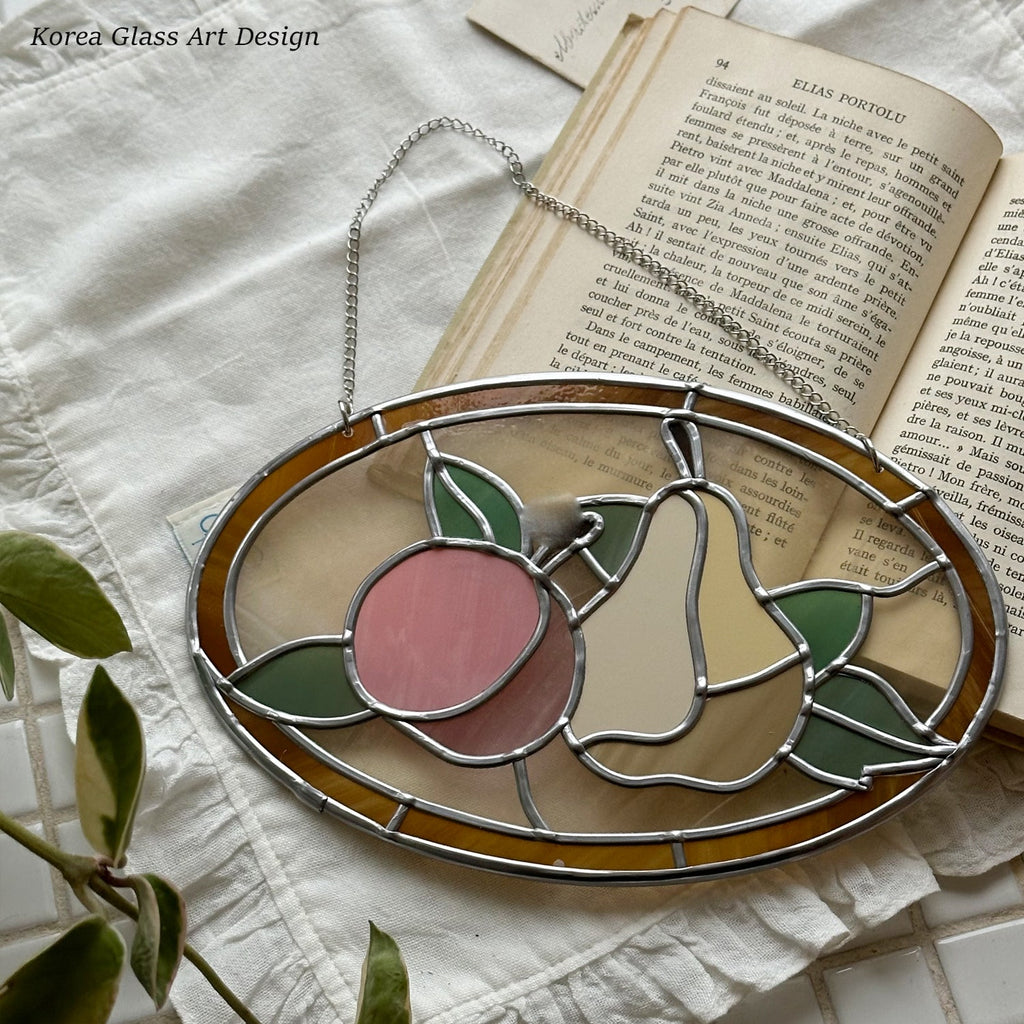 Stained glass panel with peach and pear design on a book